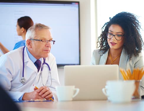 Doctor and clinic employee looking at laptop computer.