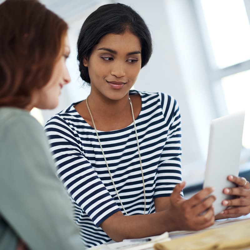 business women and men in meeting sharing phone tablet