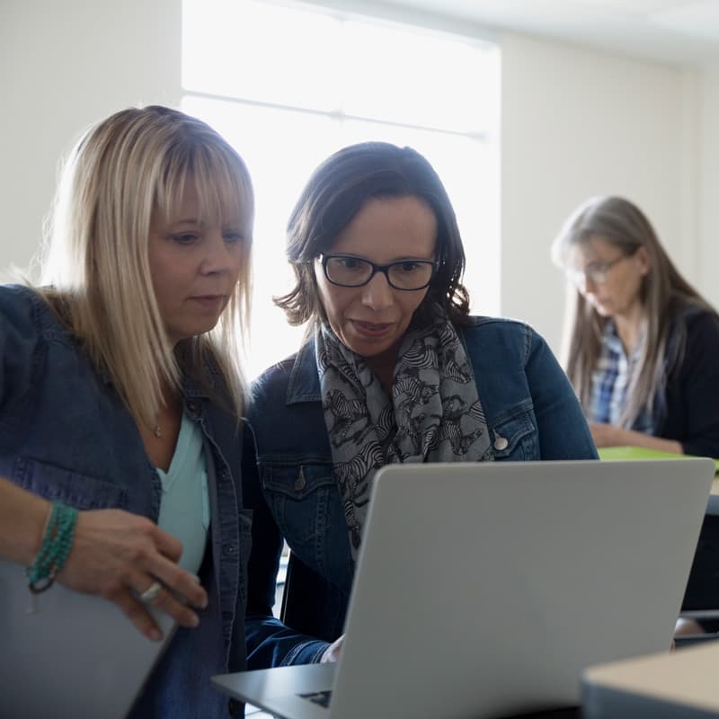 teachers working on laptops in classroom