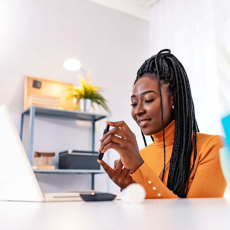 woman checking her blood glucose levels remotely at home while on her laptop