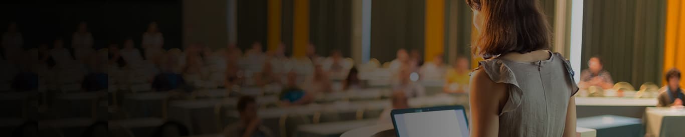 Woman teaching in lecture hall with laptop in front of her