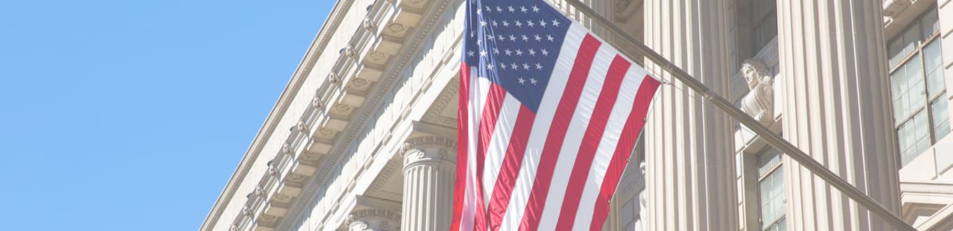 Close up of USA flag with courthouse columns in background and blue sky