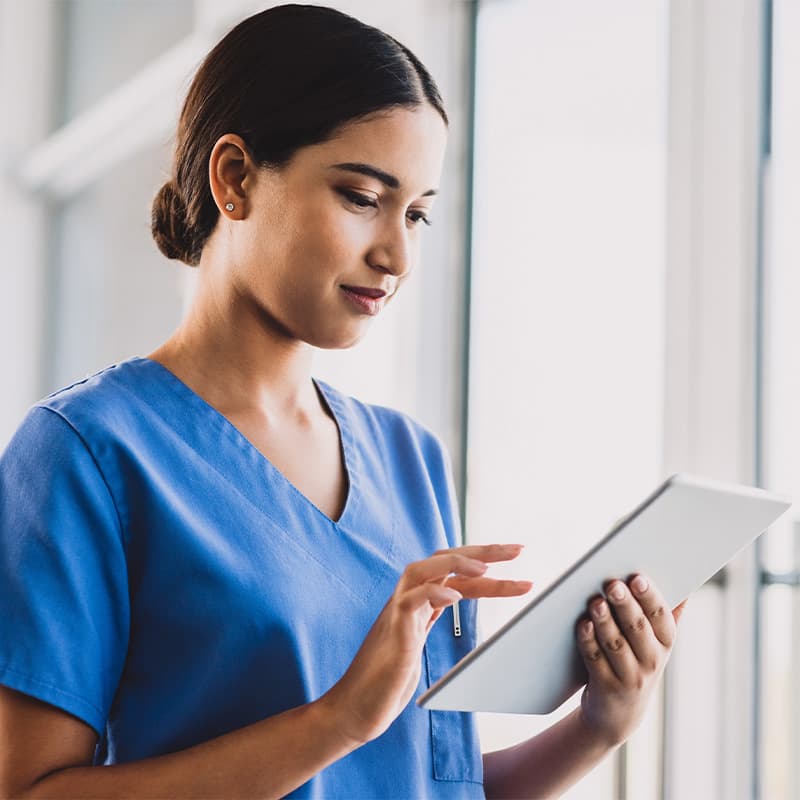 A medical professional working on a tablet, in her hands