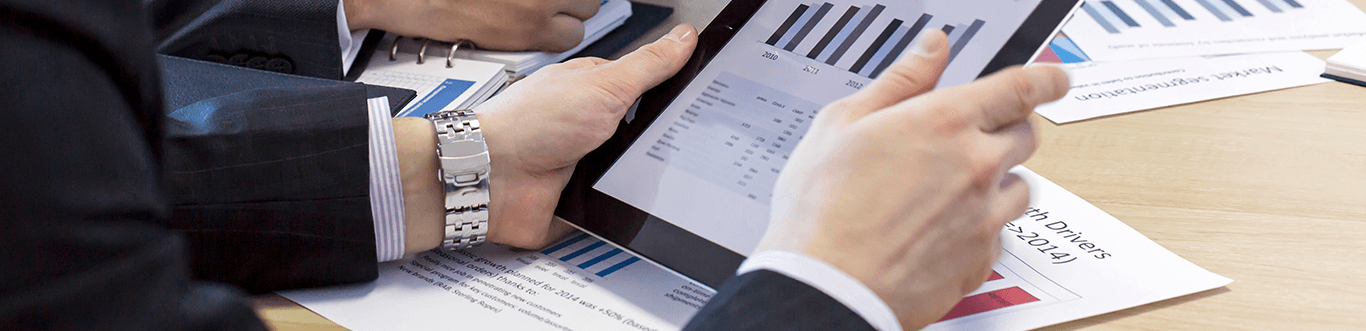 Closeup photo of a man holding a tablet displaying graphs.